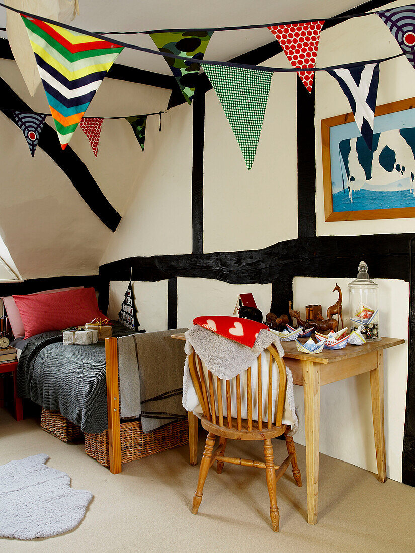 Single bed with desk and chair in childs room with bunting Herefordshire cottage, England, UK