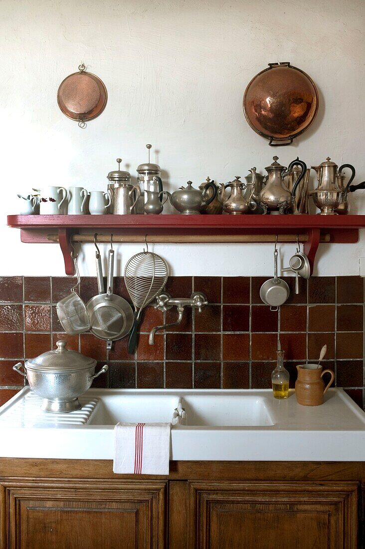 Küchenspüle und Regal mit einer Sammlung antiker Teekannen