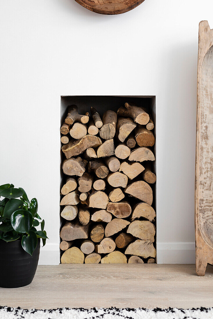 Firewood stacked in alcove in Reigate living room, Surrey, UK