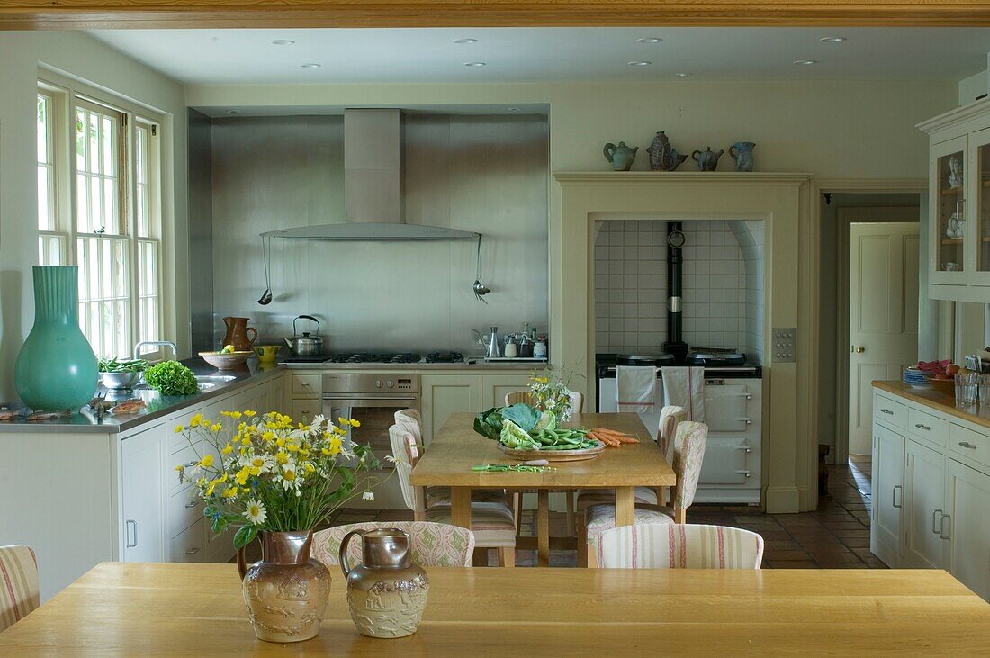 Kitchen with stove behind table with vegetables and flowers