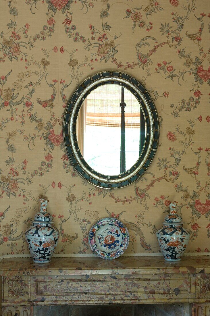 Dekoratives Porzellan auf Kamin mit Spiegel