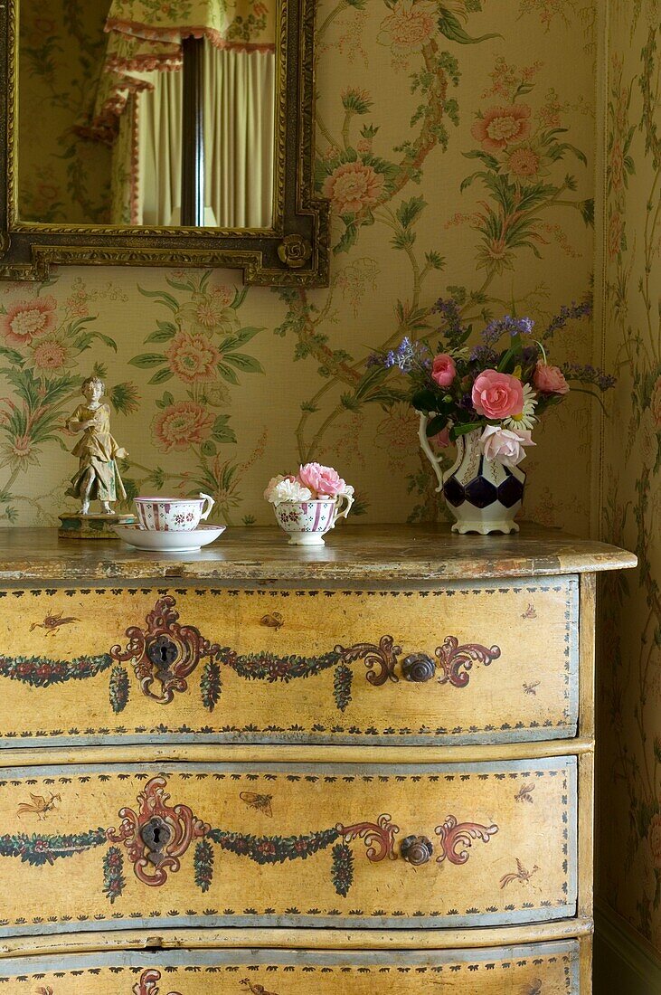 China cup and vase with flowers on dresser