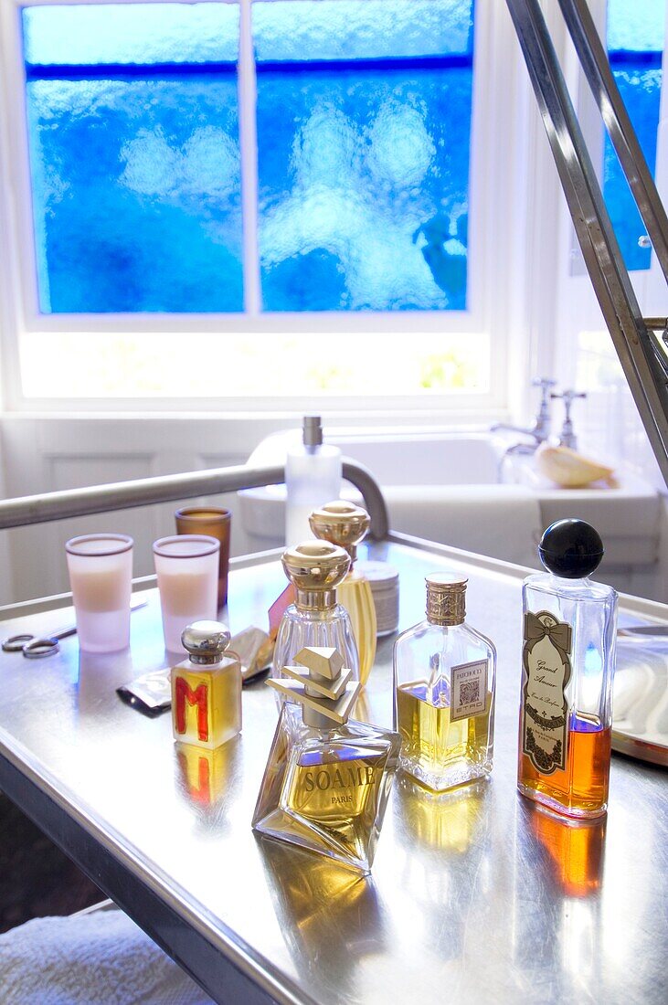 Flaschen mit Parfüms und Ölen auf einem Metallregal im Badezimmer