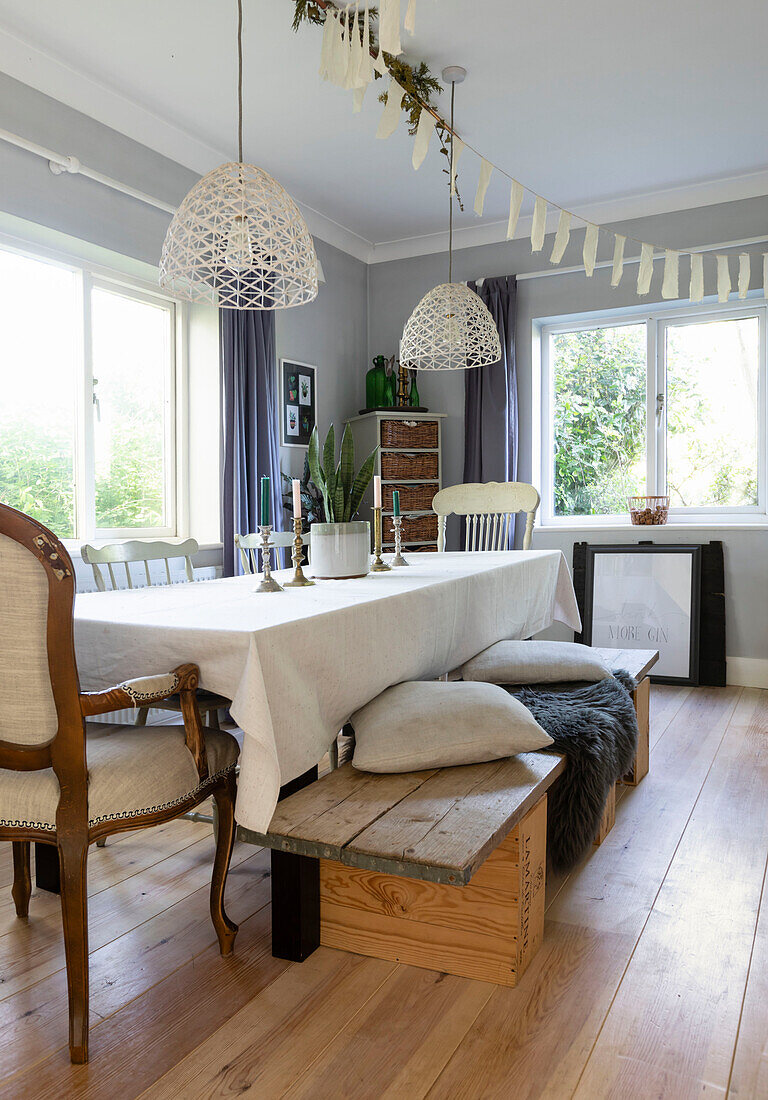 Ausziehbarer Tisch mit Sitzgelegenheiten aus recycelten Weinkisten und weißen Pendelleuchten im Esszimmer in Colchester, Essex, UK