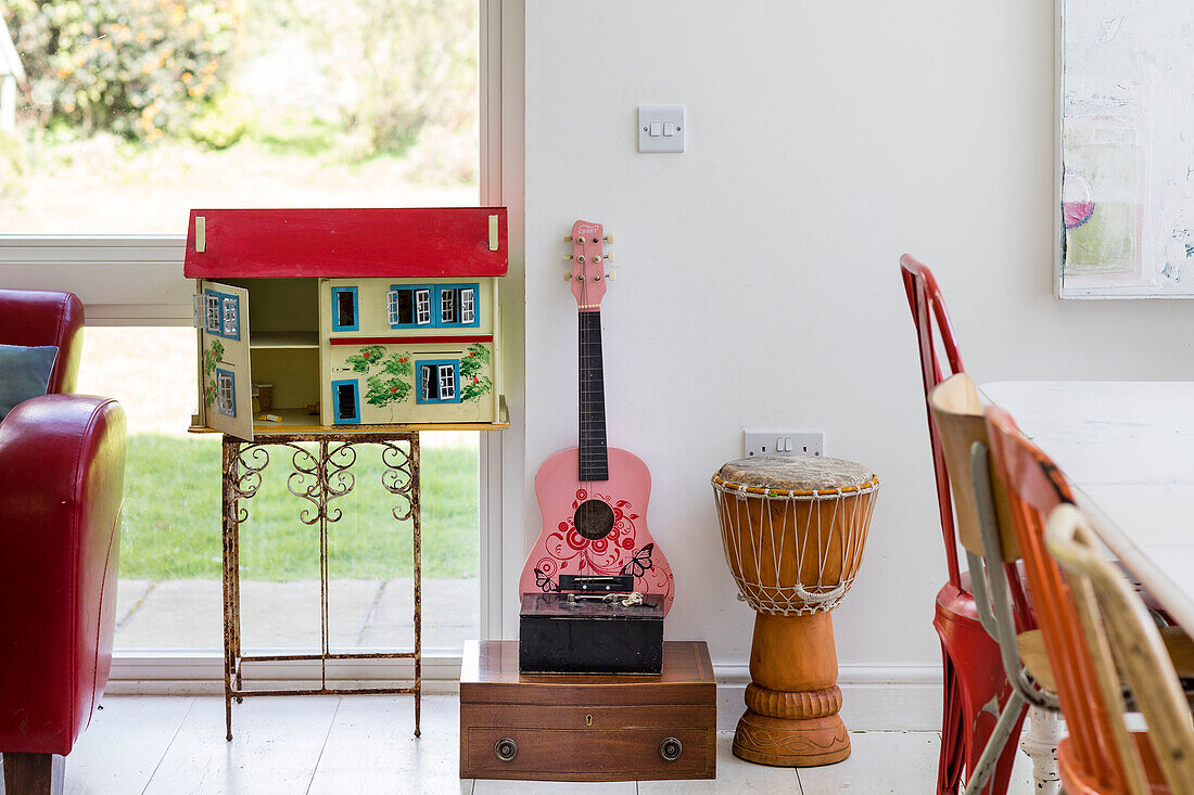 Puppenhaus und Gitarre mit Trommel im Fenster eines Hauses in Guildford, Surrey (UK)