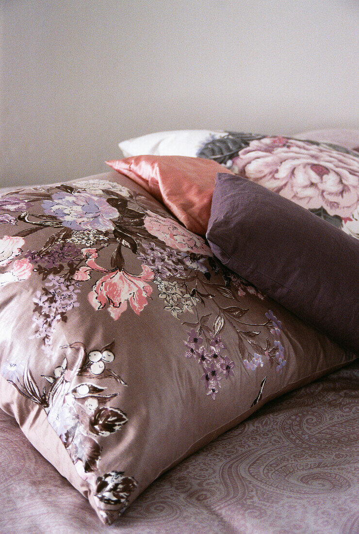 Bedroom detail with floral cushions in tones of pink and purple
