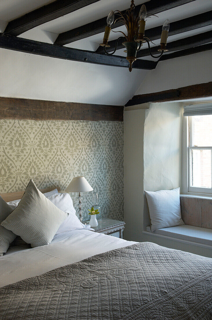 Window seat and quilted bed in Hastings cottage with beamed ceiling