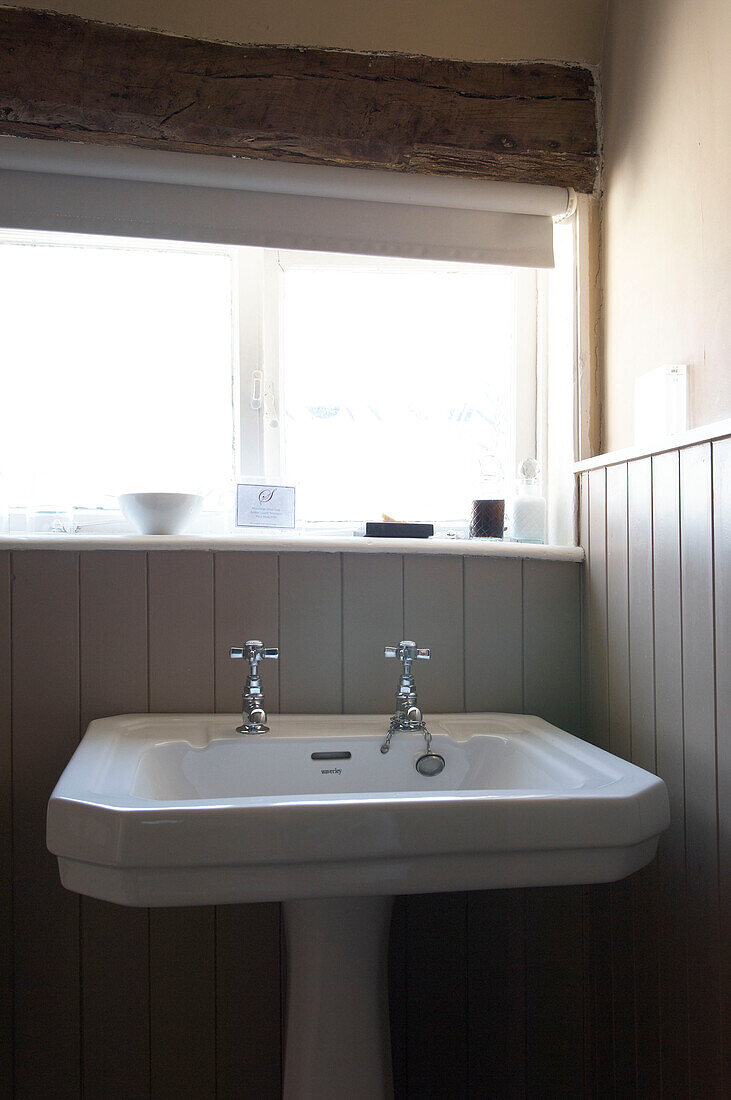 Pedestal-base wash-basin at window of Hastings bathroom with tongue and groove panelling