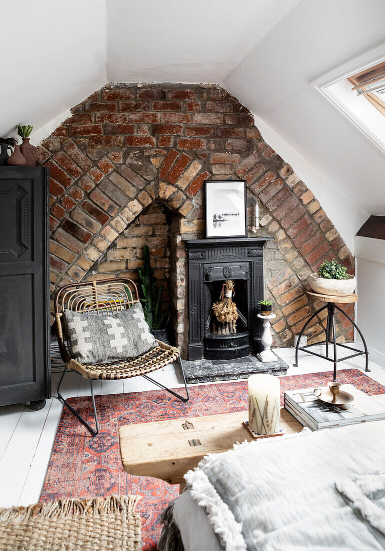 Attic bedrooom with exposed brick wall and Victorian cast iron fireplace and cane chair in Cardiff Wales UK