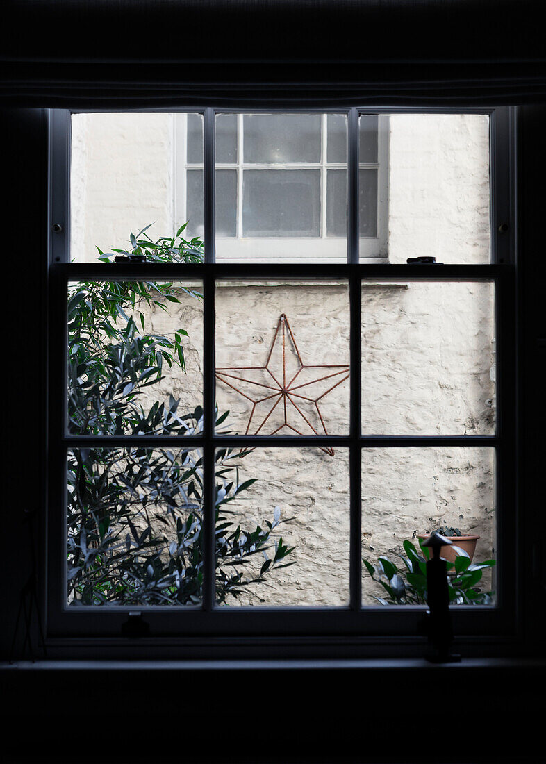 Christmas star viewed through window from dark interior Somerset UK
