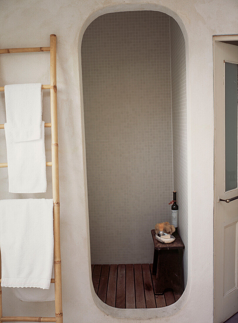 Weiß gefliestes Badezimmer mit Duschkabine, Handtuchhalter und Fußbodenbelag