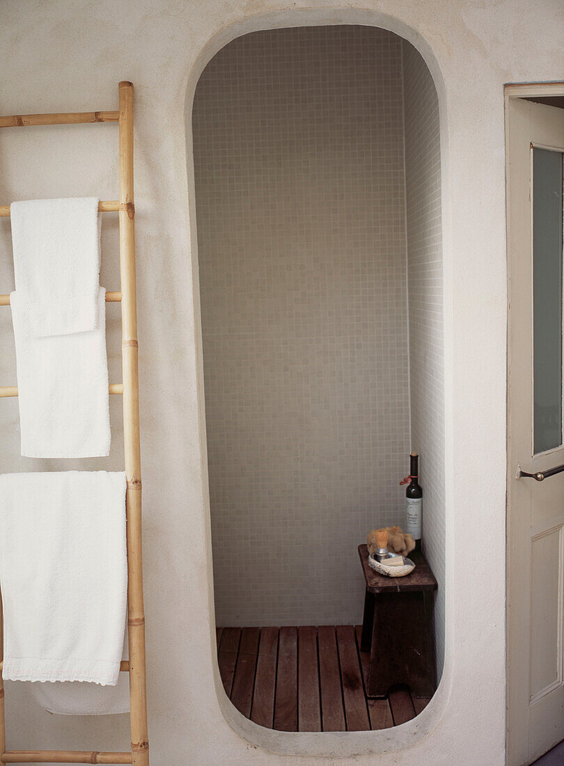 White tiled bathroom shower cubicle with towel rail and decked floor