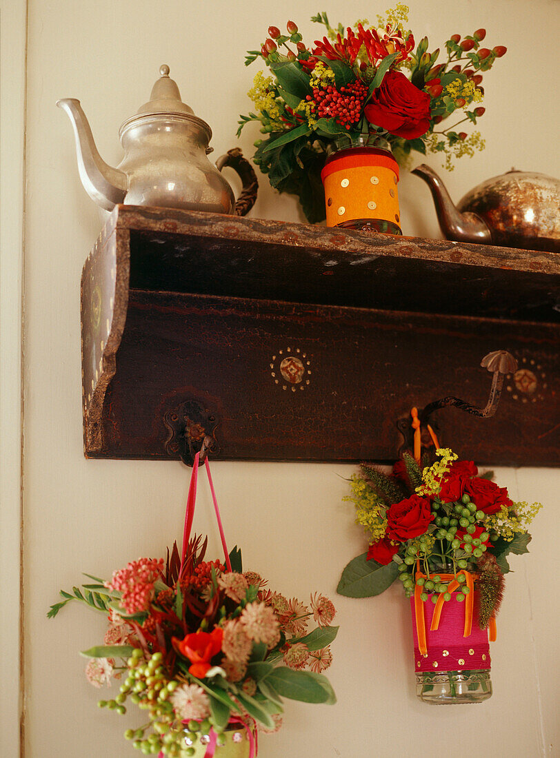 Bunte hängende Blumenarrangements an antiken rustikalen Kleiderhaken