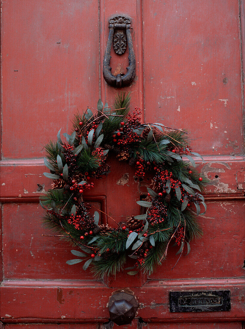 Weihnachtskranz an einer rustikalen, abgenutzten roten Tür