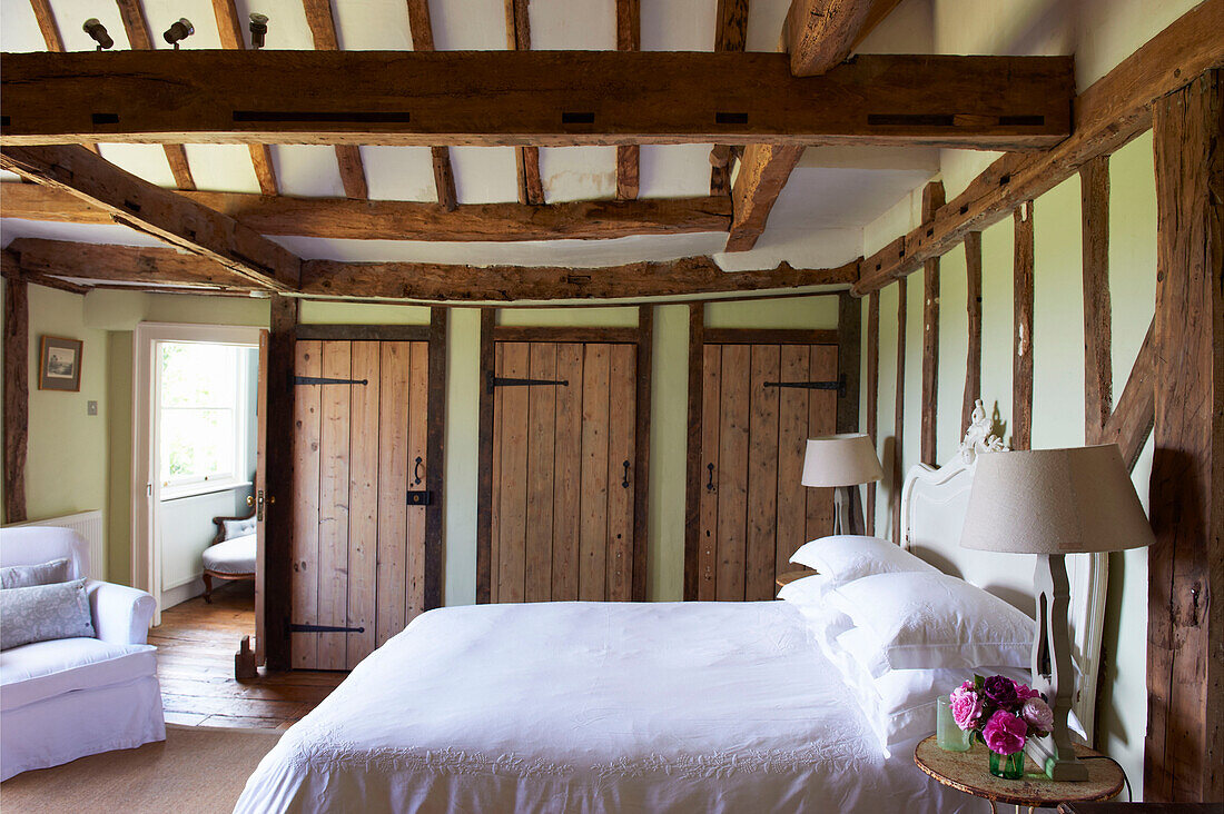 Double bed under beamed ceiling in Iden farmhouse, Rye, East Sussex, UK