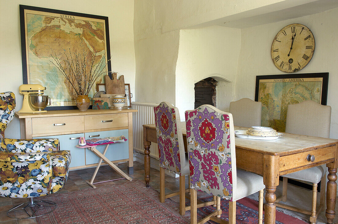 Chairs upholstered in vintage fabric with wall maps in Suffolk dining room, England, UK