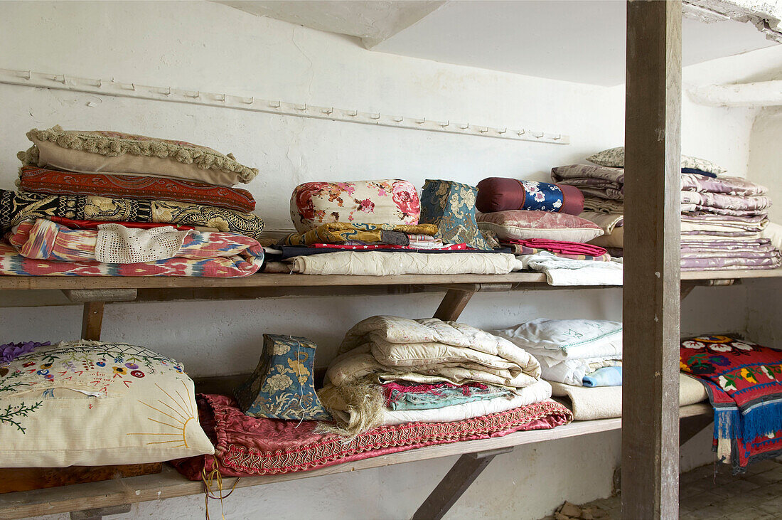 Gefaltete Textilien auf einem Regal in einem Haus in Suffolk, England, UK