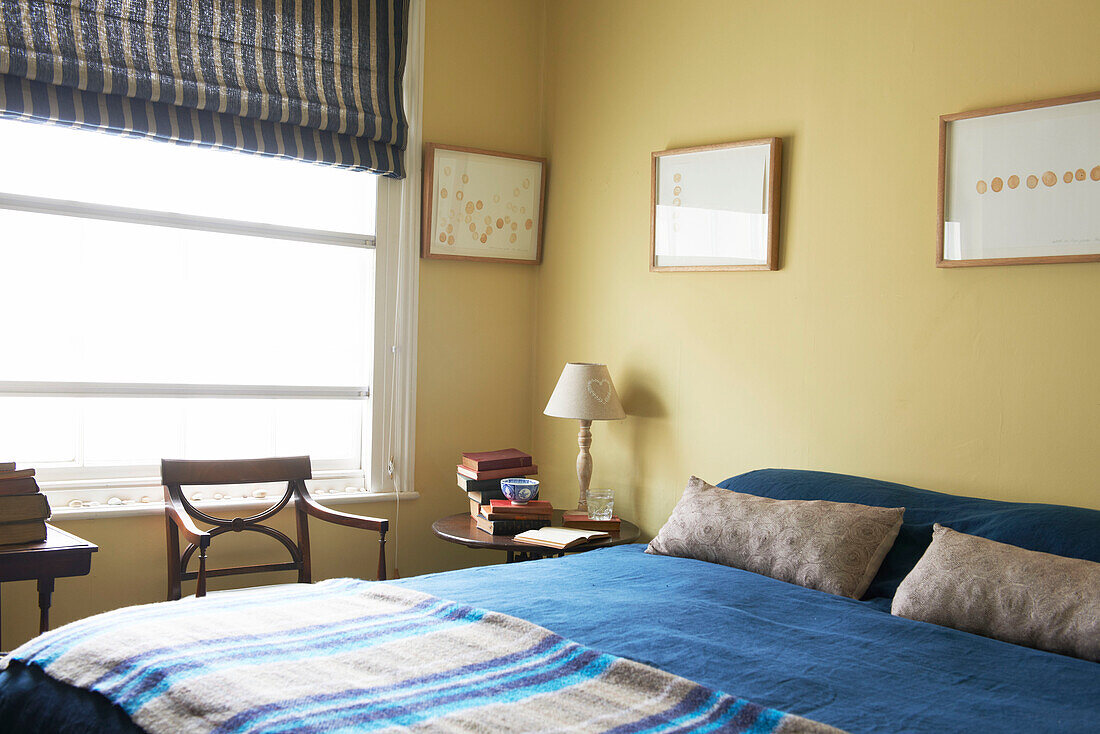 Schottenmuster und blaue Bettbezüge im gelben Schlafzimmer eines Hauses in Aldeburgh, Suffolk, England, UK