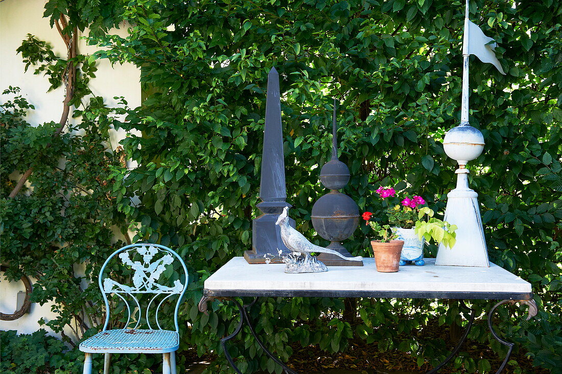 Ornaments on table with chair in garden of Massachusetts home, New England, USA