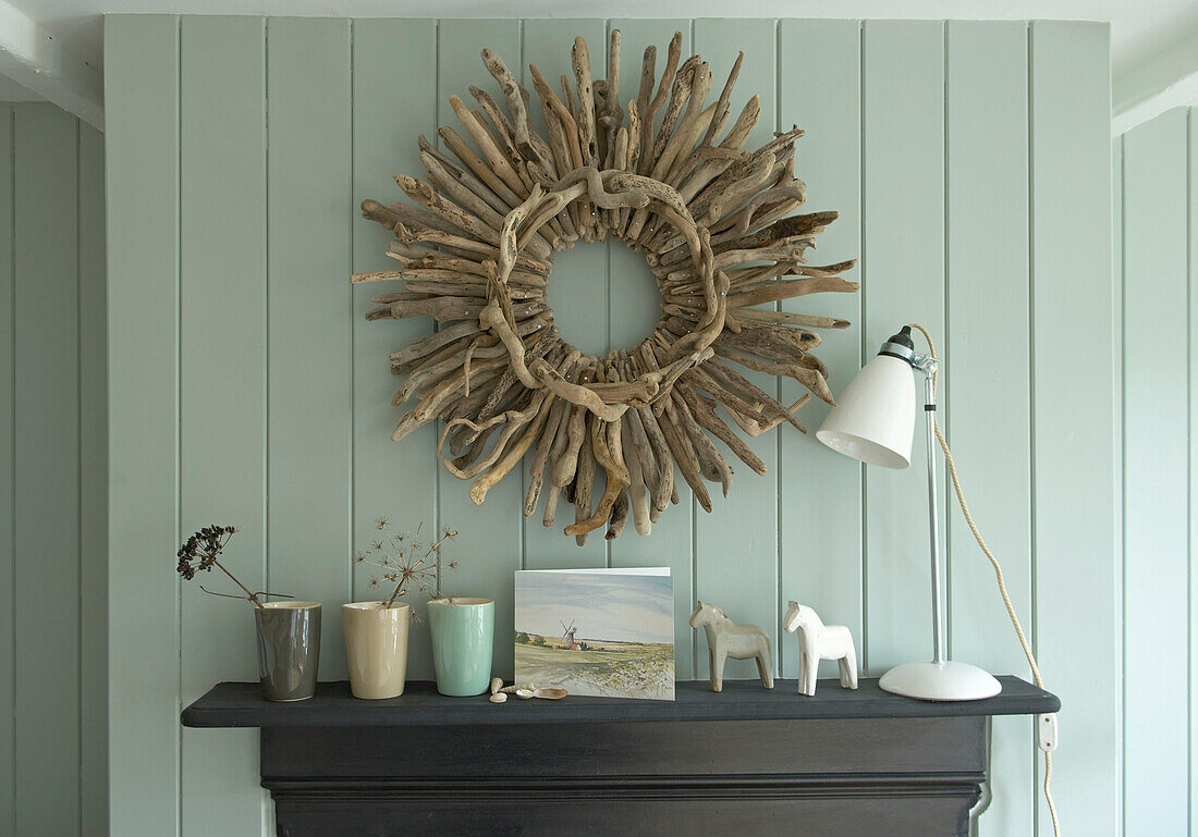 Rustic display of driftwood and homewares on a mantelpiece with painted wood panelled walls