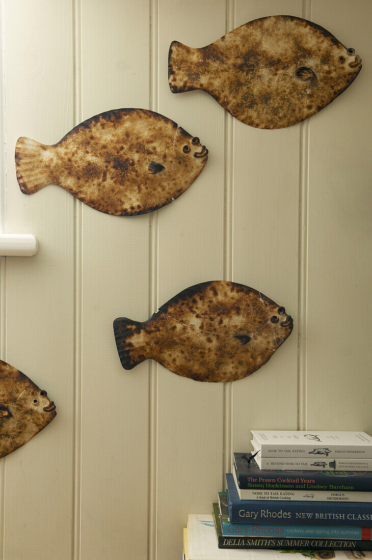 Wall mounted fish ornaments and a stack of books in Hastings beach house England UK