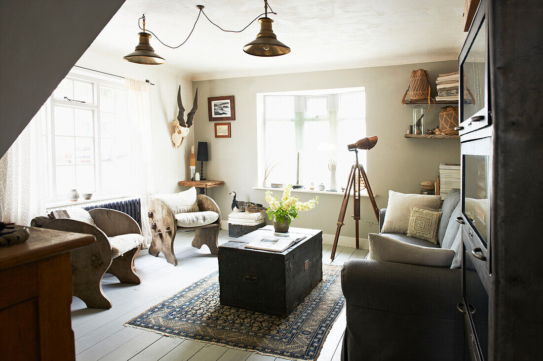 Reisetruhe auf Teppich mit zwei Holzstühlen im Wohnzimmer in Hastings, East Sussex, England, UK