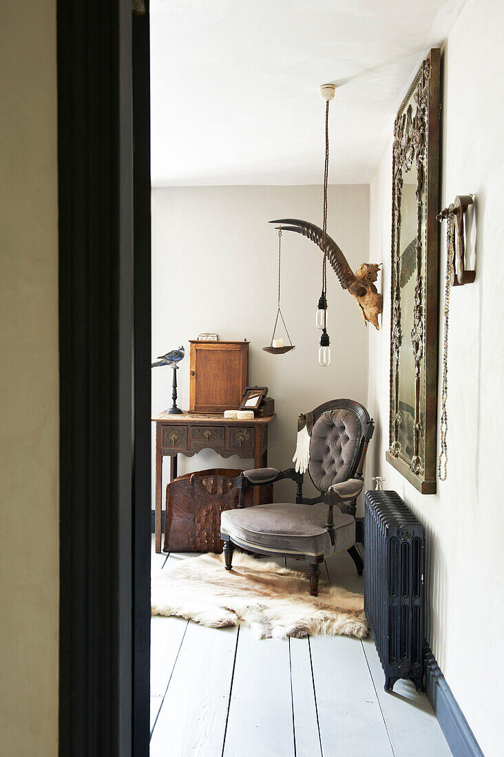 Geknöpfter Sessel mit Vintage-Spiegel über dem Heizkörper in einem Haus in Hastings, East Sussex, England, UK