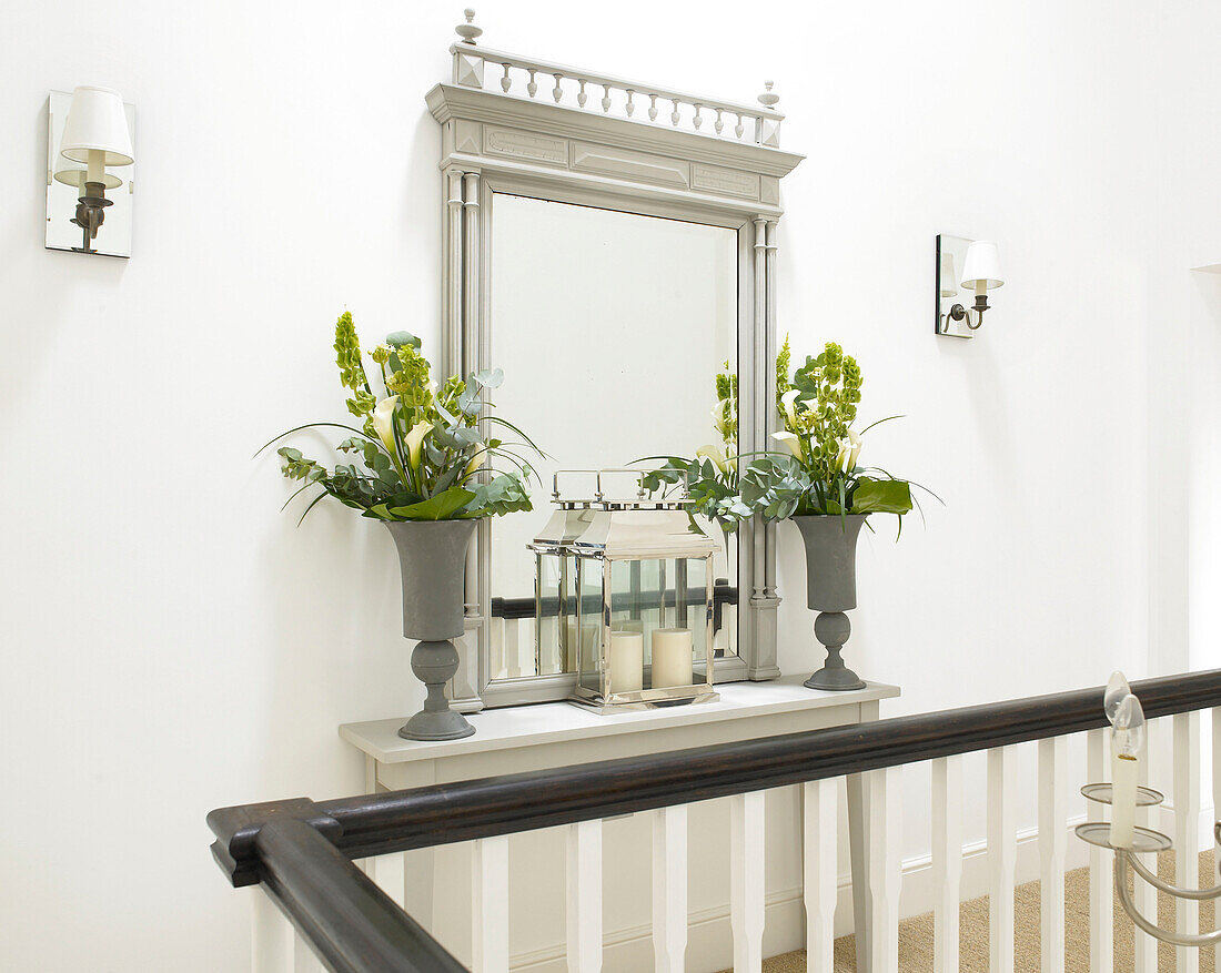Laterne und zwei Vasen mit Blumen vor einem großen Spiegel