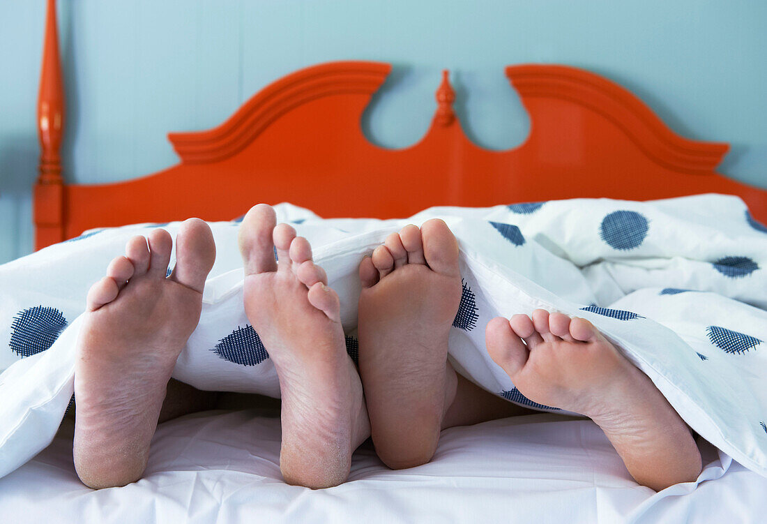 Pärchen mit Füßen unter der Bettdecke in den Berkshires, Massachusetts, Connecticut, USA