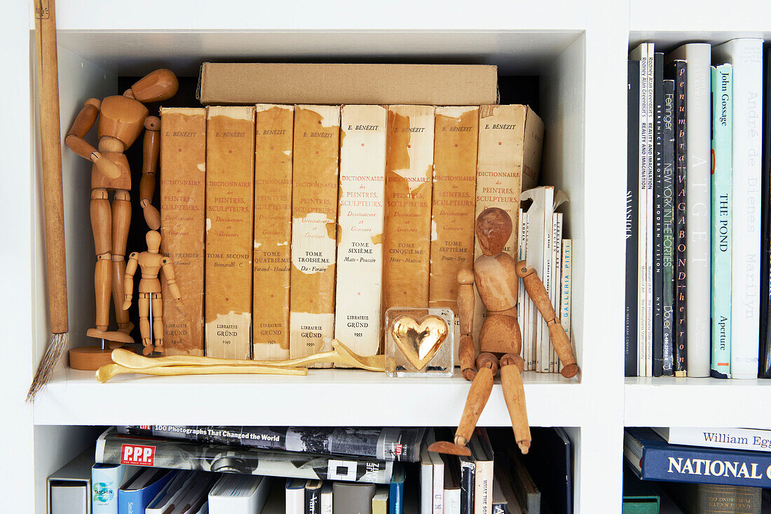 Wooden lay figures on bookshelf with ageing hardbacks in Austerlitz, Columbia County, New York, United States