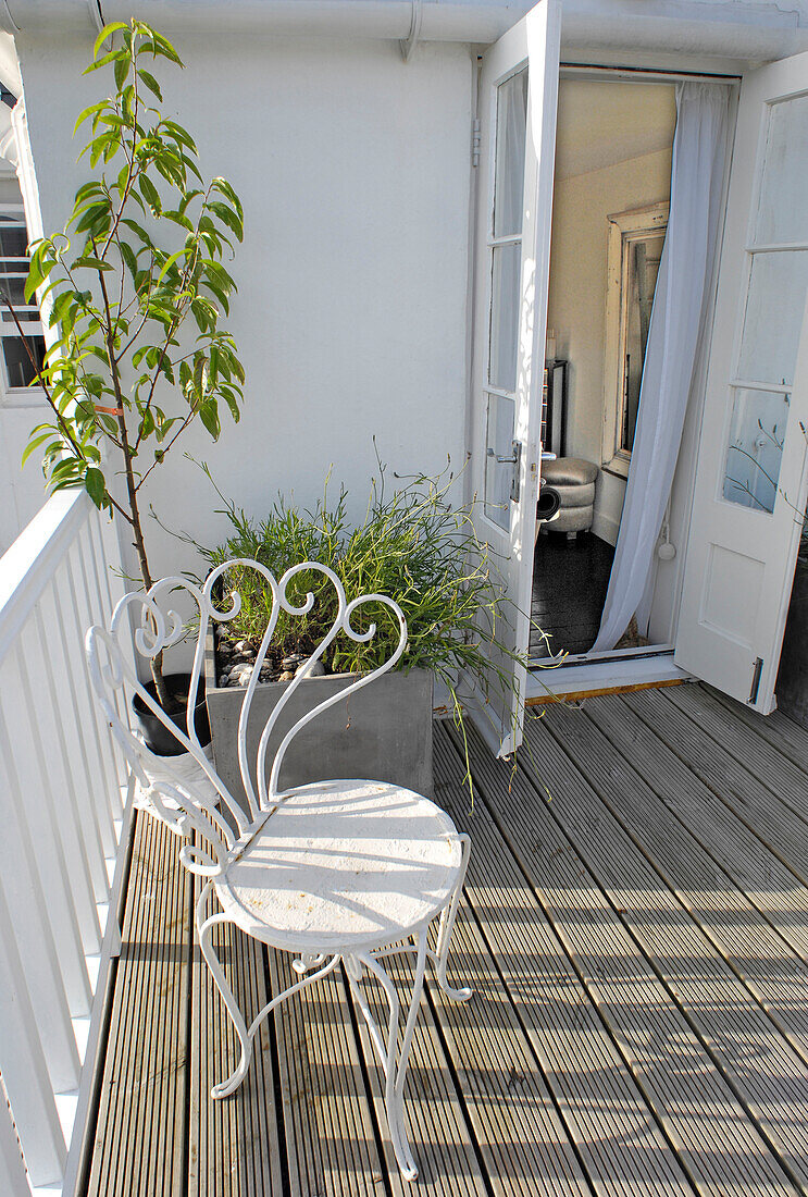 Überdachter Gartenbalkon an einem Cottage am Meer mit weißem Drahtgeflechtstuhl in Dover, UK
