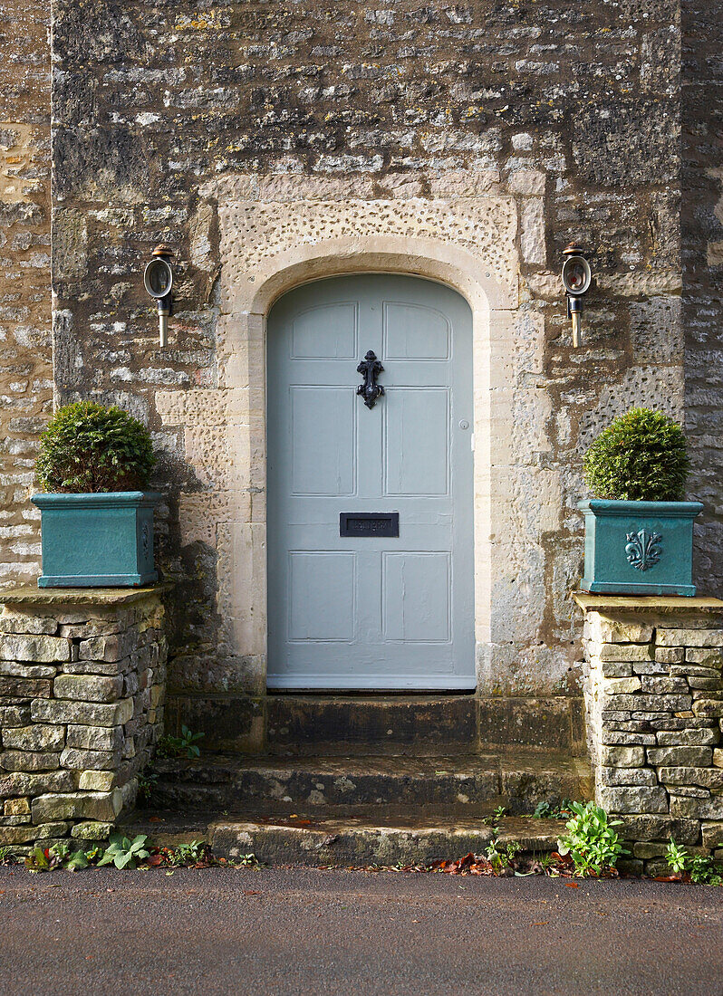 Hellblaue Eingangstür eines Bauernhauses aus Stein in Gloucestershire, England, UK
