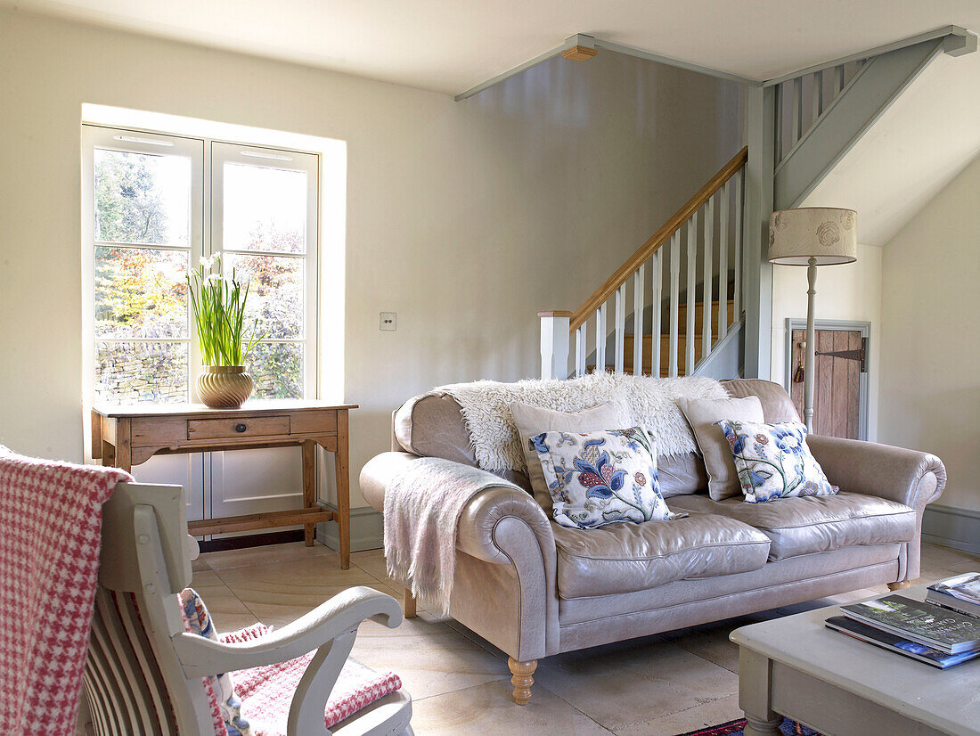 Leather sofa in open plan living room of Gloucestershire farmhouse, England, UK