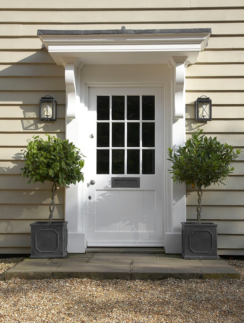 Weiße Haustür und Topfpflanzen vor einem Bauernhauses mit Holzverkleidung in Hampshire, England, UK