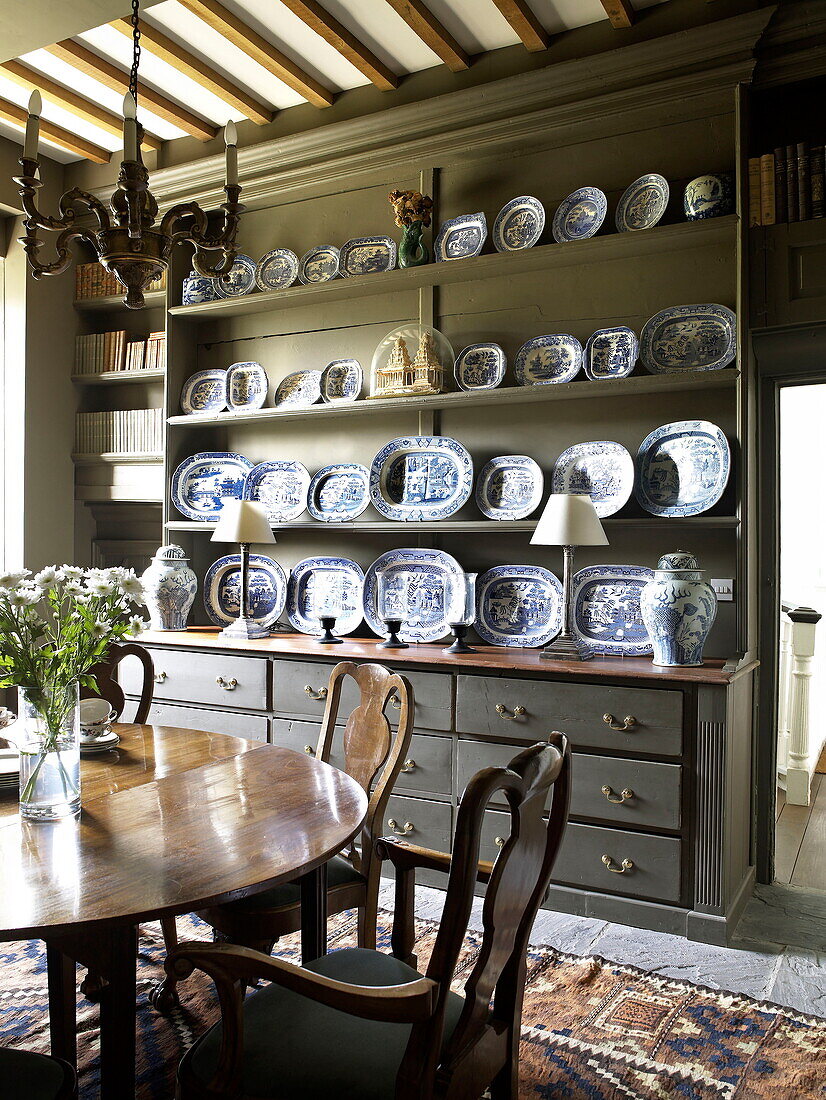 Chinaware on painted dresser with wooden dining table in Laughame townhouse, Wales, UK