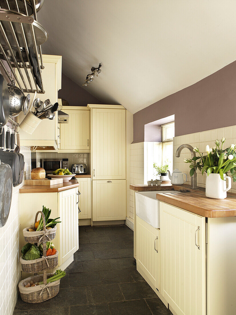 Pfannenständer und Gemüsekorb in der Pantryküche eines walisischen Cottage, UK