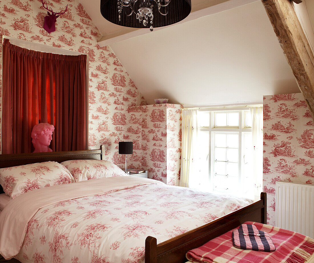 Toile de Jouy wallpaper and patterned duvet on bed in Welsh cottage, UK