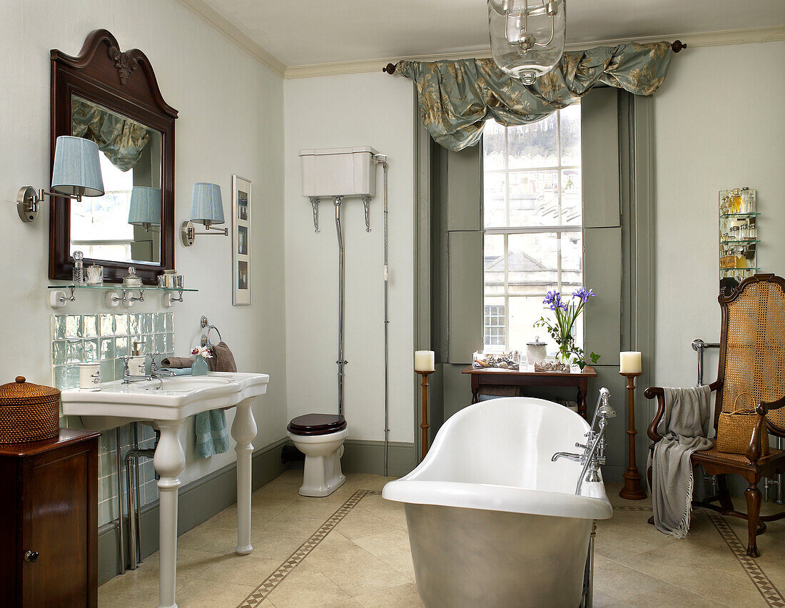 Freistehende Badewanne und wandmontierter Spülkasten im Badezimmer eines Hauses in der Stadt Bath, Somerset, Großbritannien