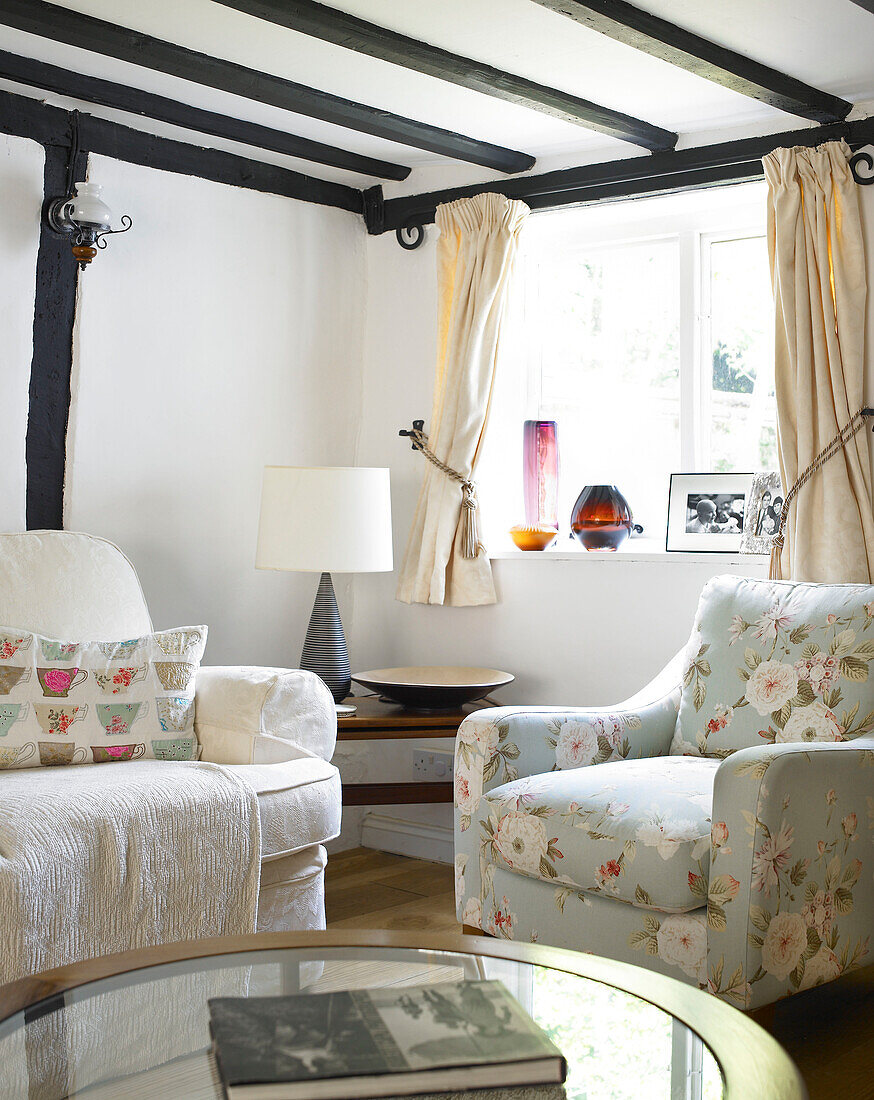 Floral armchair at window in timber-framed living room Buckinghamshire cottage England UK