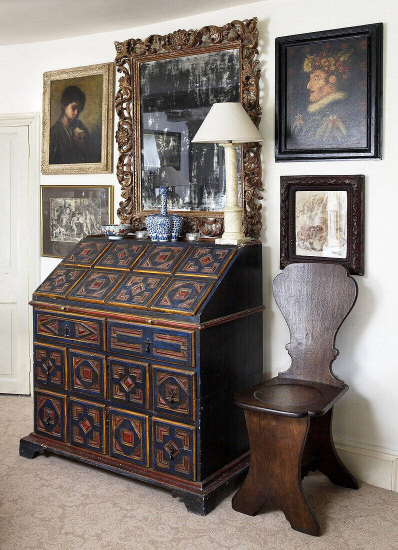 Antike Schreibkommode und Holzstuhl mit Kunstwerken in einem Haus in Gloucestershire, England, UK