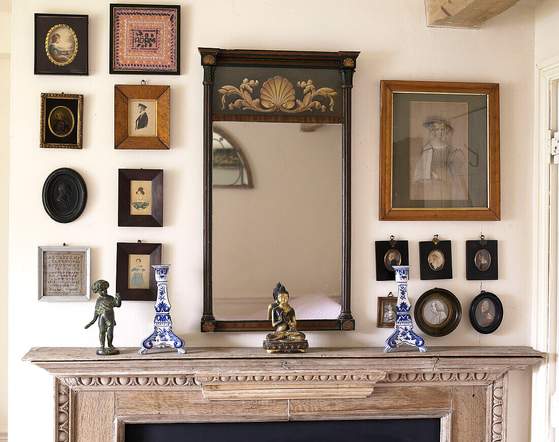 Antique mirror and artwork with ornaments above mantlepiece in Gloucestershire farmhouse, England, UK