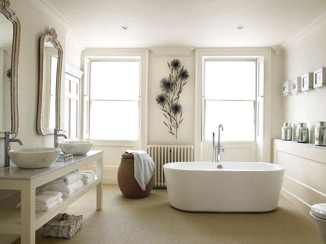 Freistehende Badewanne mit geblümten Wänden und Doppelwaschbecken im Badezimmer eines modernen Hauses in Bath, Somerset, England, UK