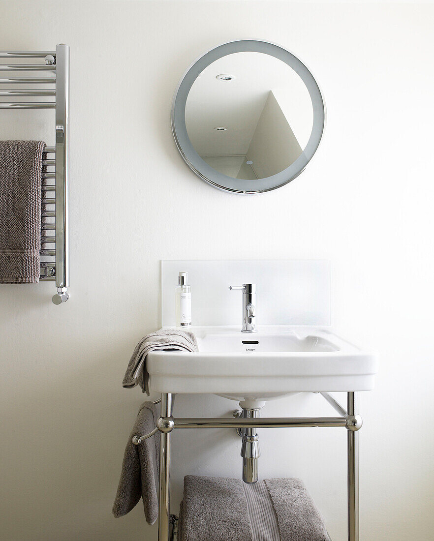 Runder Spiegel und wandmontierter Heizkörper mit Waschtisch im Badezimmer eines modernen Hauses in Bath Somerset, England, UK