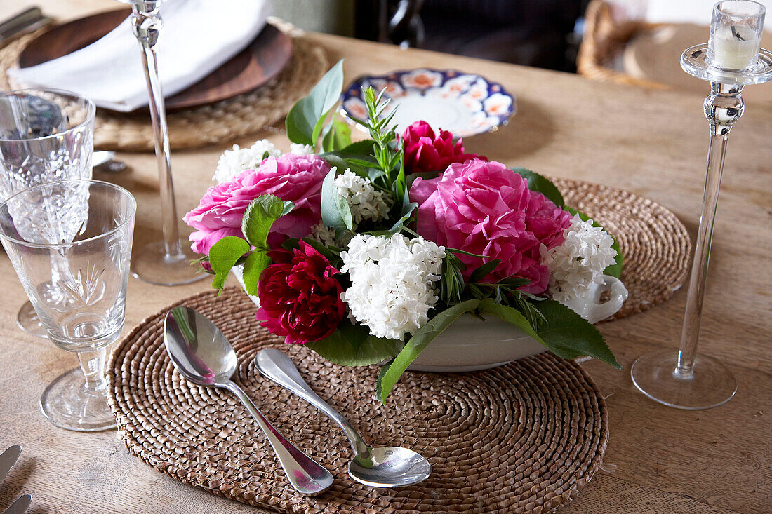 Pink and white centrepiece with glassware on dining room table in country house Suffolk, England, UK