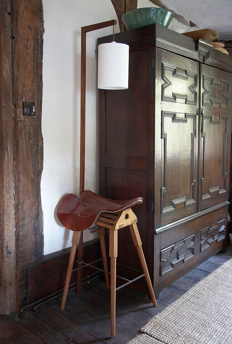 Saddle stand and carved wardrobe in hallway of country house Suffolk, England, UK