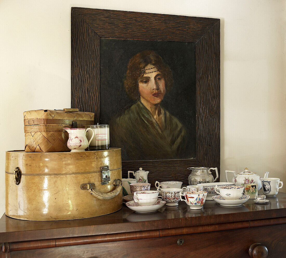 Chinaware with vintage hat box and oil painting on sideboard in country house Suffolk, England, UK