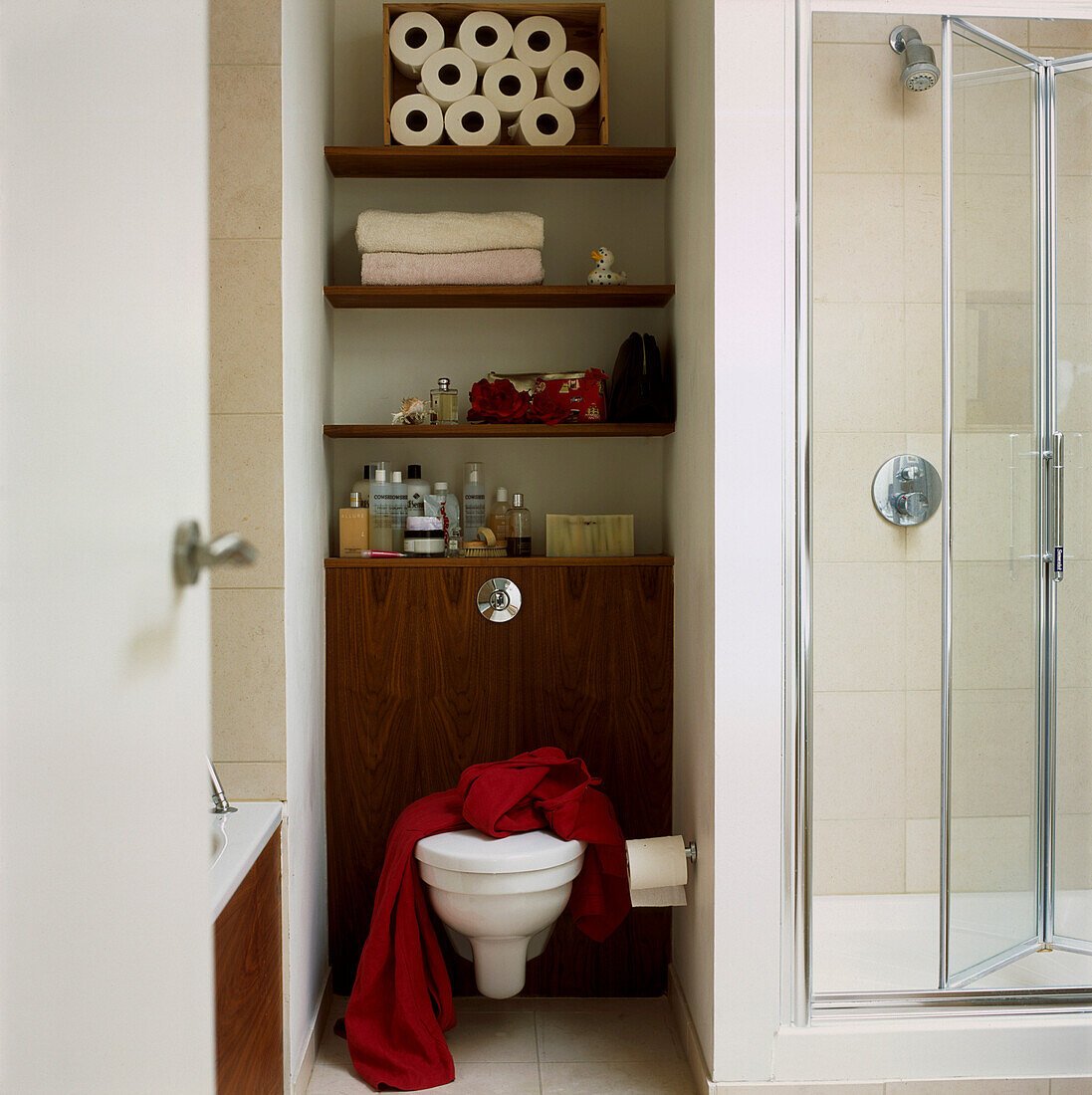 Modern small bathroom with toilet storage shelving and shower cubicle