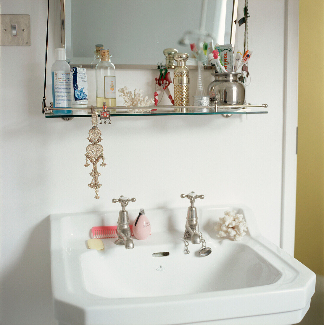 Detail of period bathroom sink and vanity mirror with small storage shelf for toiletries 