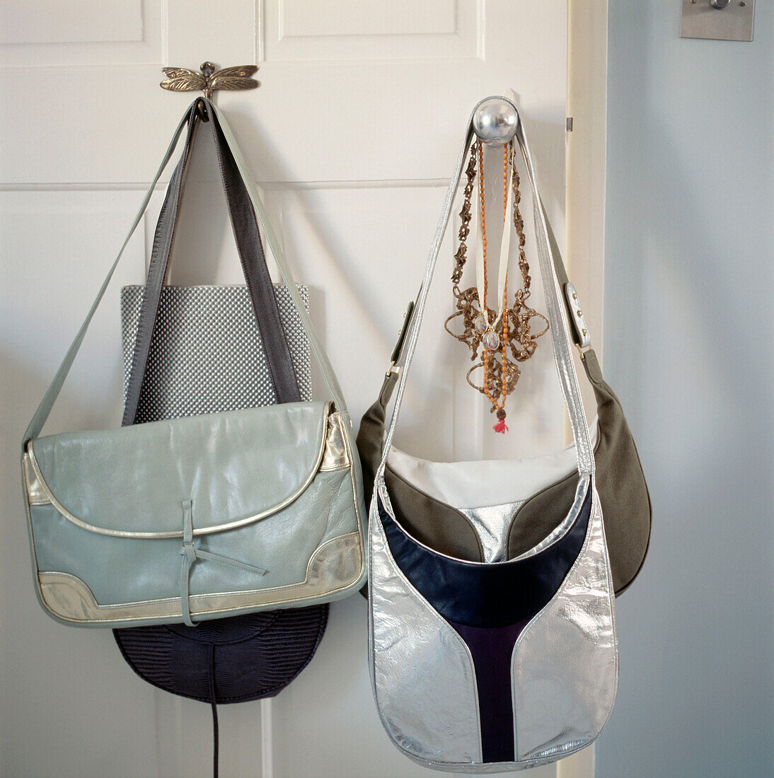 Handtaschen hängen an einem Türknauf an einer weißen Tür
