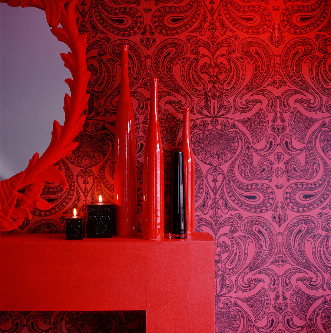 Detail of a red and black coordinating living room with mantelpiece and home wares
